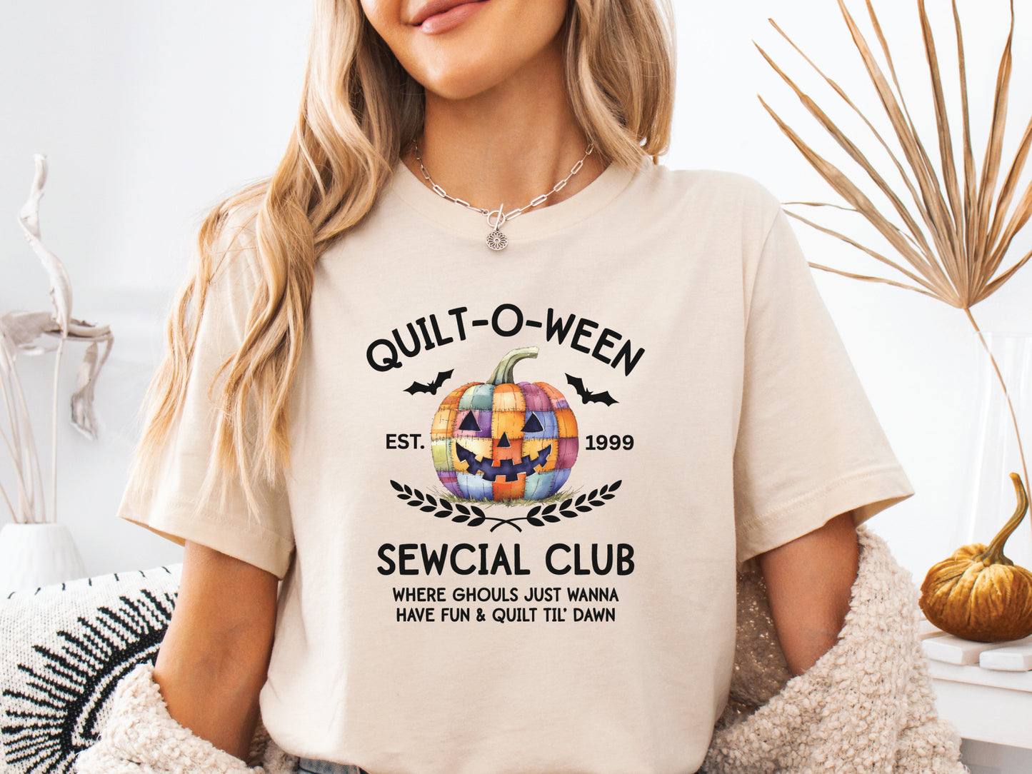 Quilt-O-Ween Sewcial Club shirt from Bee Inspired Tees, designed in ivory with a colorful patchwork jack-o’-lantern, bats, and playful Halloween typography—perfect gift for quilters.