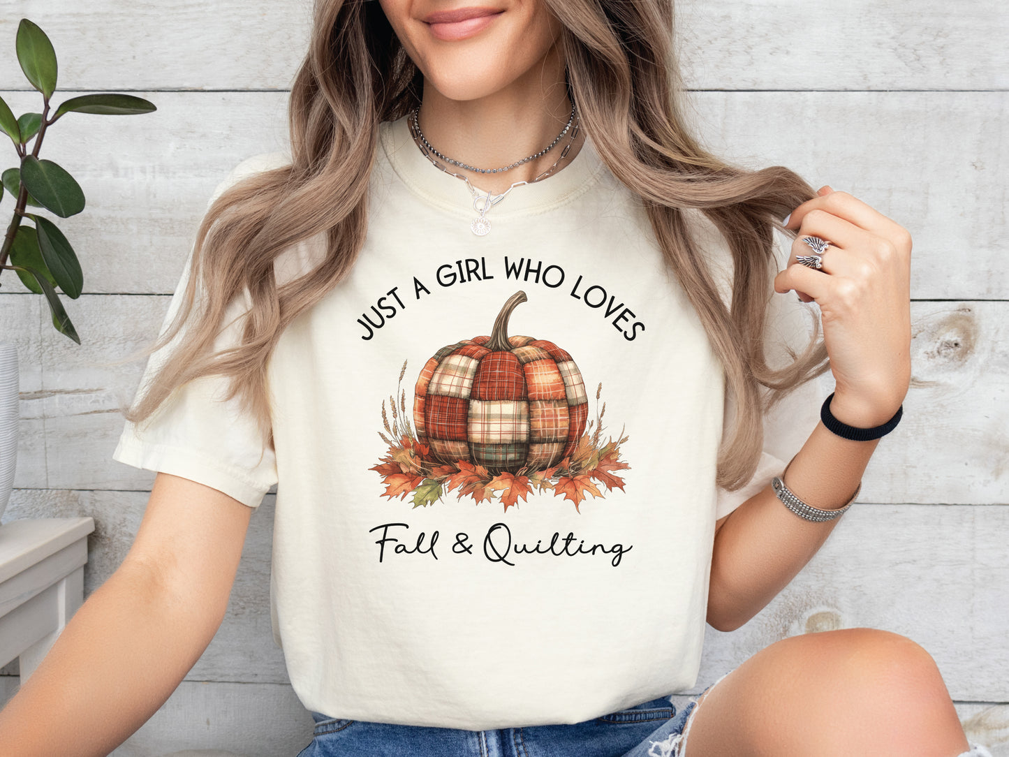 Ivory colored t-shirt from Bee Inspired Tees with the phrase “Just a Girl Who Loves Fall & Quilting,” featuring a plaid pumpkin surrounded by autumn leaves. Perfect fall gift for quilters and ideal for quilt retreats or sewing days.