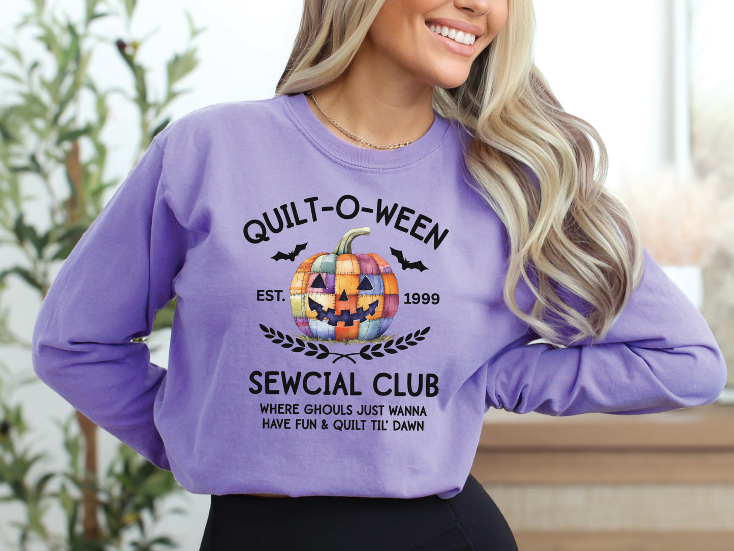 Quilt-O-Ween Sewcial Club long sleeve Violet colored shirt from Bee Inspired Tees, featuring a colorful patchwork jack-o’-lantern, bats, and playful Halloween typography—fun gift for quilters.