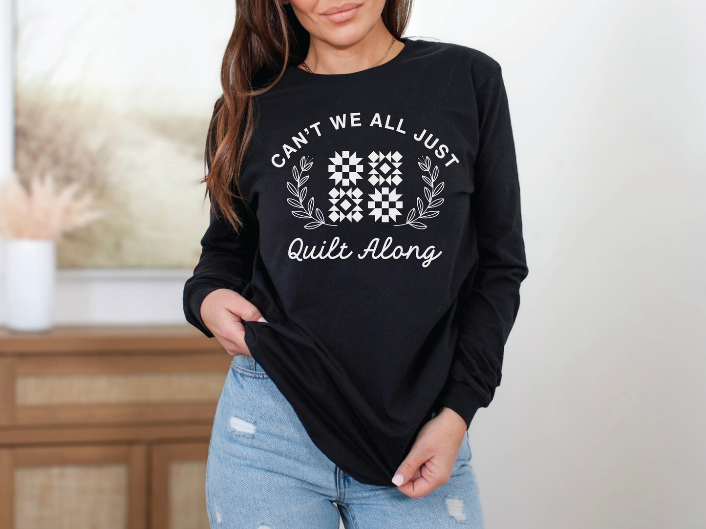 Cozy quilt-themed long sleeve black t-shirt with the phrase “Can’t We Just All Quilt Along,” perfect gift for a quilter, ideal for sewing days, quilt retreats, and craft fairs.
