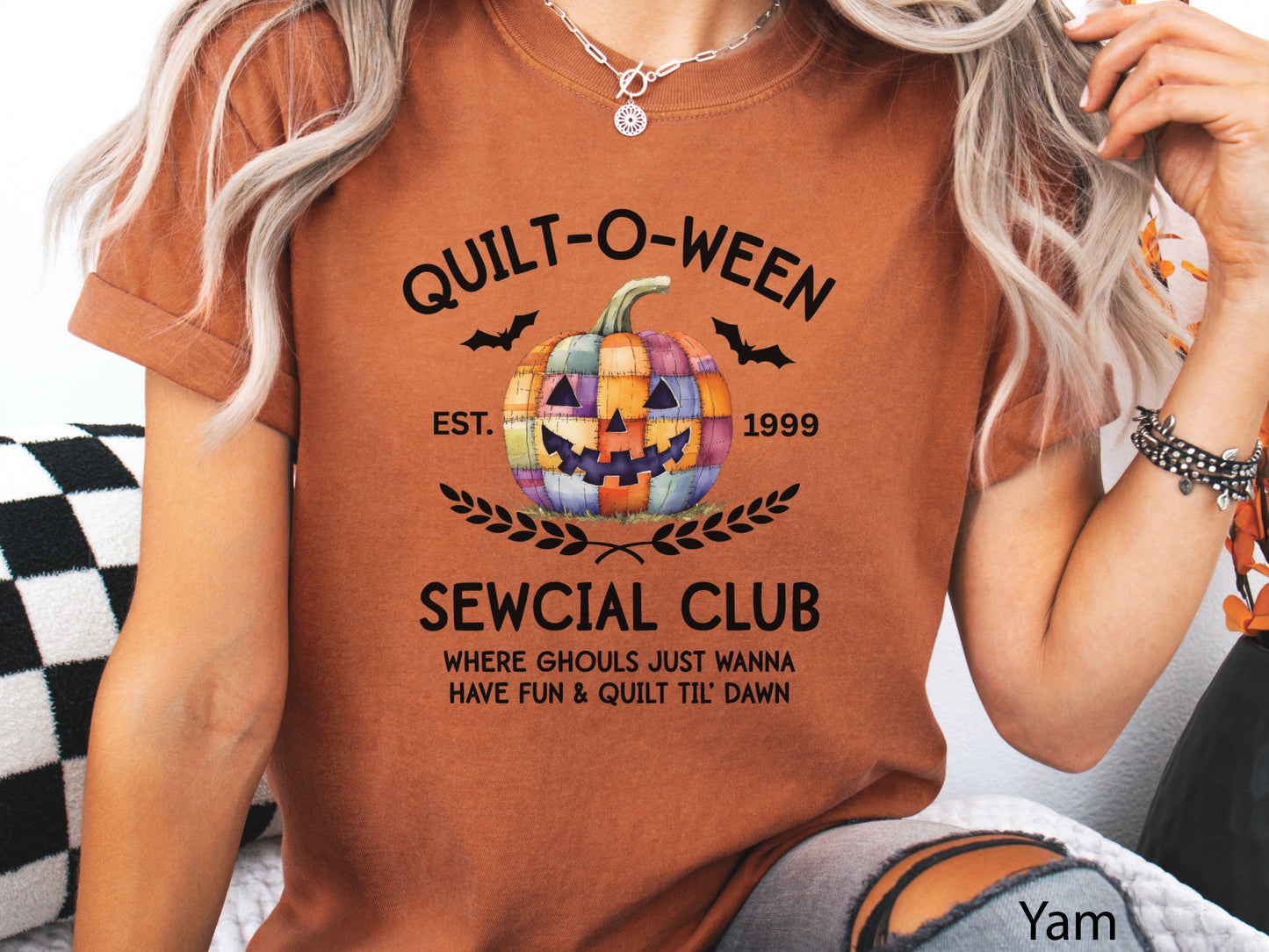 Quilt-O-Ween Sewcial Club shirt from Bee Inspired Tees, designed in Autumn hues (Yam) with a colorful patchwork jack-o’-lantern, bats, and playful Halloween typography—perfect gift for quilters.