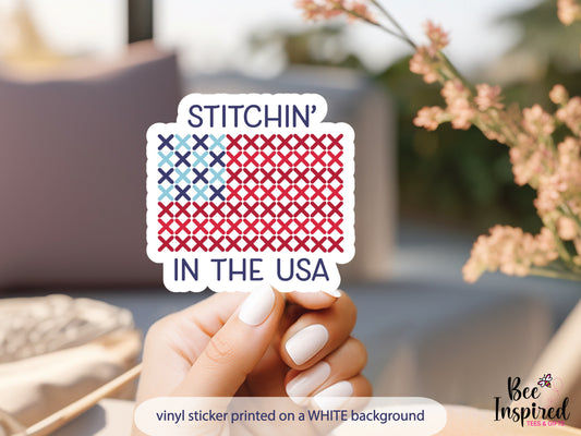 Patriotic “Stitchin’ In The USA” vinyl sticker with American flag stitching design on a white background, perfect for sewing, cross stitch, and needlepoint lovers celebrating America’s 250th.