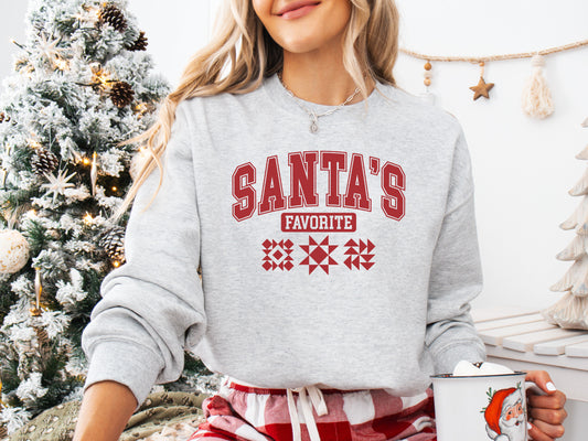 Cozy Ash (gray) colored Christmas sweatshirt with the phrase “Santa’s Favorite” in bold red varsity letters and three quilt block designs, perfect for quilters celebrating the holidays in handmade style.