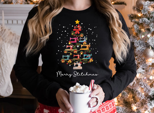 Black long sleeve shirt with a Christmas tree made of colorful sewing machines and the words “Merry Stitchmas” — festive holiday gift for quilters and sewists.
