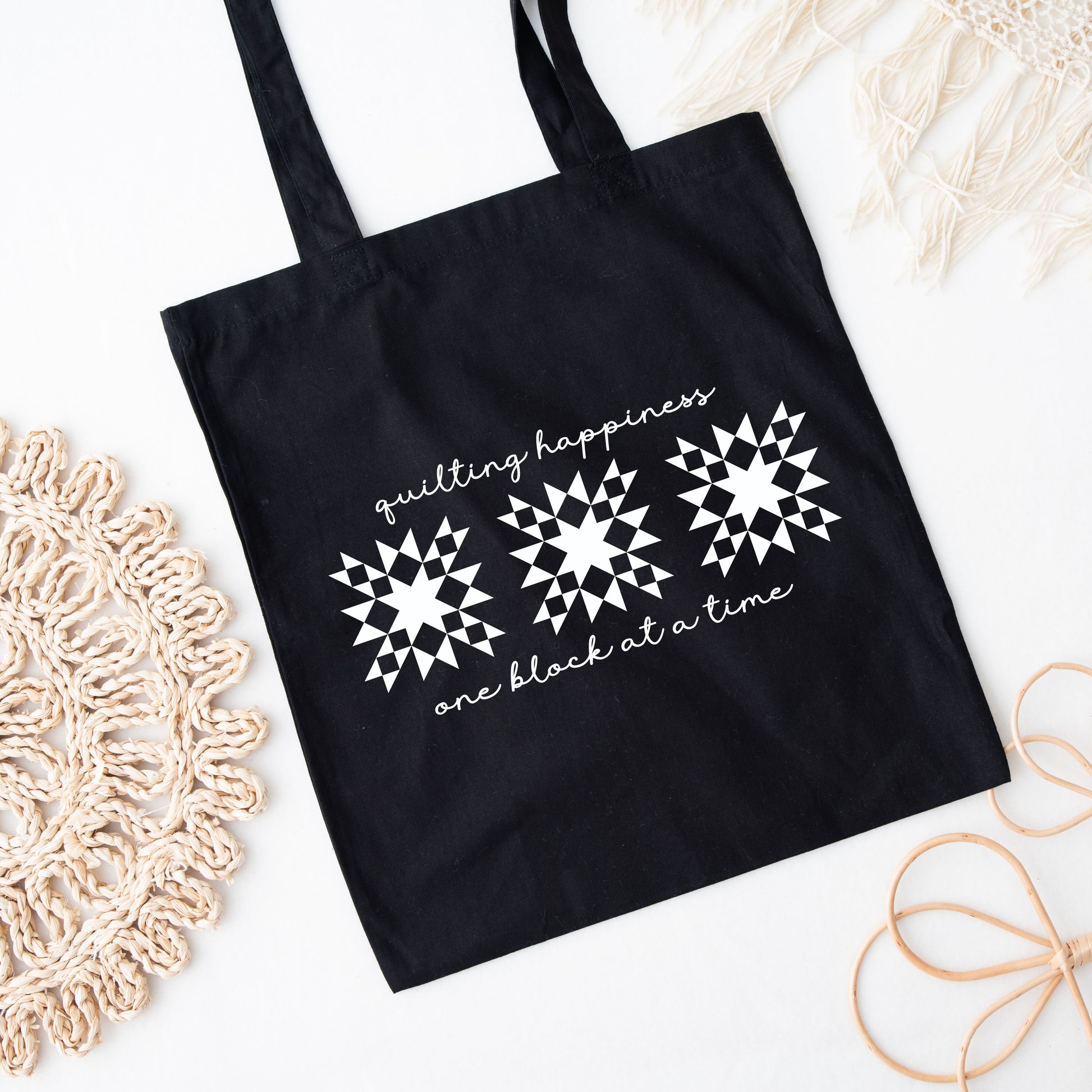 Carry your quilting joy wherever you go with this black canvas tote bag! Featuring the heartwarming phrase “Quilting Happiness, One Block at a Time.