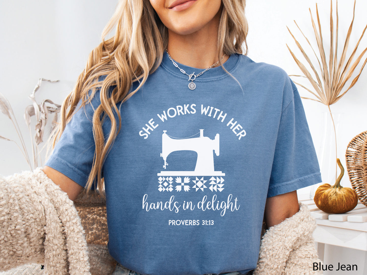 A t-shirt featuring a vintage-style sewing machine, quilt block icons, and the verse “She works with her hands in delight – Proverbs 31:13.”