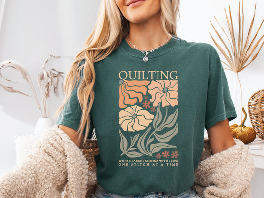 Boho quilting short sleeve t-shirt featuring a floral design and the phrase “Quilting, Where Fabric Blooms With Love, One Stitch at a Time.” 