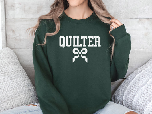 Quilter sweatshirt with varsity-style lettering and a quilty coquette bow, a cozy and stylish gift for quilters to wear at retreats, guilds, or while sewing at home.