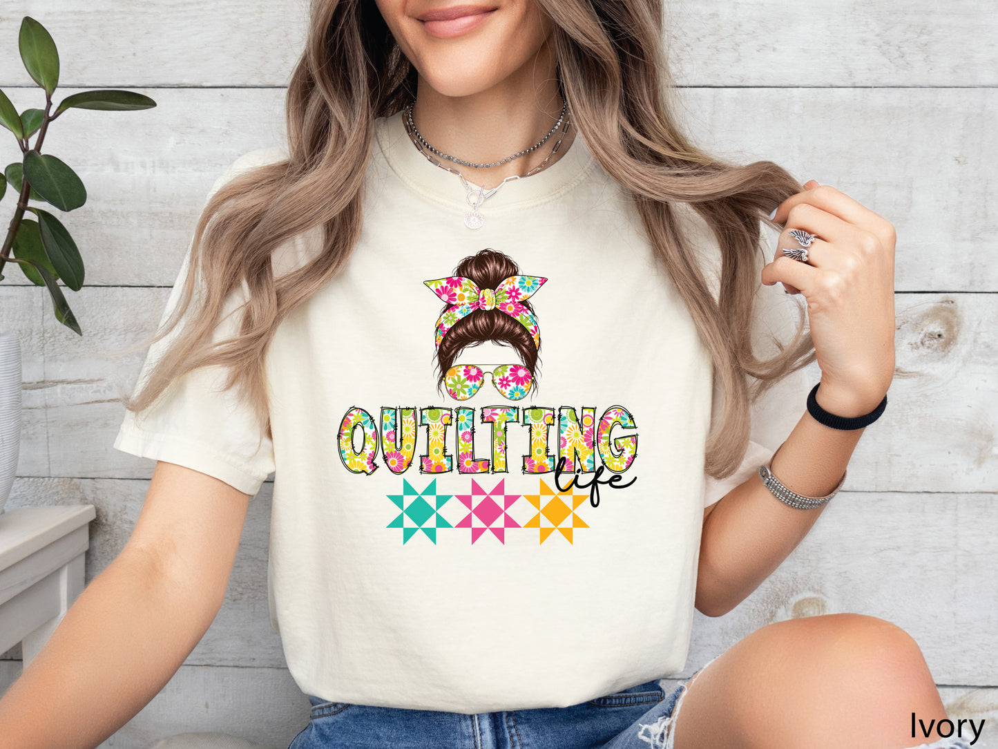 Celebrate your love of quilting with this cheerful Quilting Life t-shirt! Featuring a stylish messy bun, colorful floral headband, coordinating sunglasses, and bright quilt block accents, this fun design is perfect for quilters, fabric lovers, and anyone who feels most at home in their sewing room.