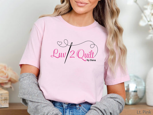 Official Luv2Quilt by Dana quilting-themed t-shirt featuring the Luv2Quilt logo with a sewing needle and stitched heart design, perfect for quilt classes, retreats, and everyday wear.