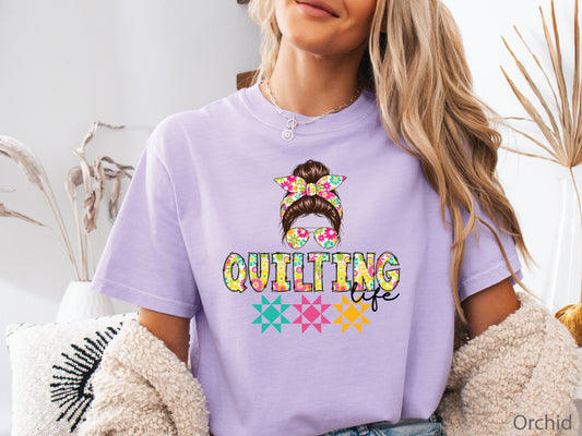 Celebrate your love of quilting with this cheerful Quilting Life t-shirt! Featuring a stylish messy bun, colorful floral headband, coordinating sunglasses, and bright quilt block accents, this fun design is perfect for quilters, fabric lovers, and anyone who feels most at home in their sewing room.