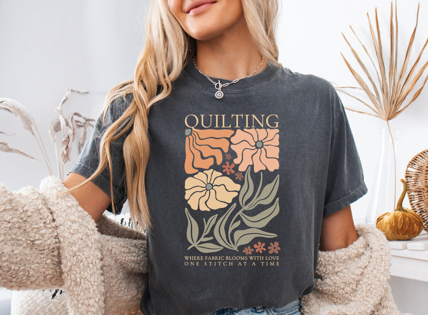 Boho quilting short sleeve t-shirt featuring a floral design and the phrase “Quilting, Where Fabric Blooms With Love, One Stitch at a Time.” 