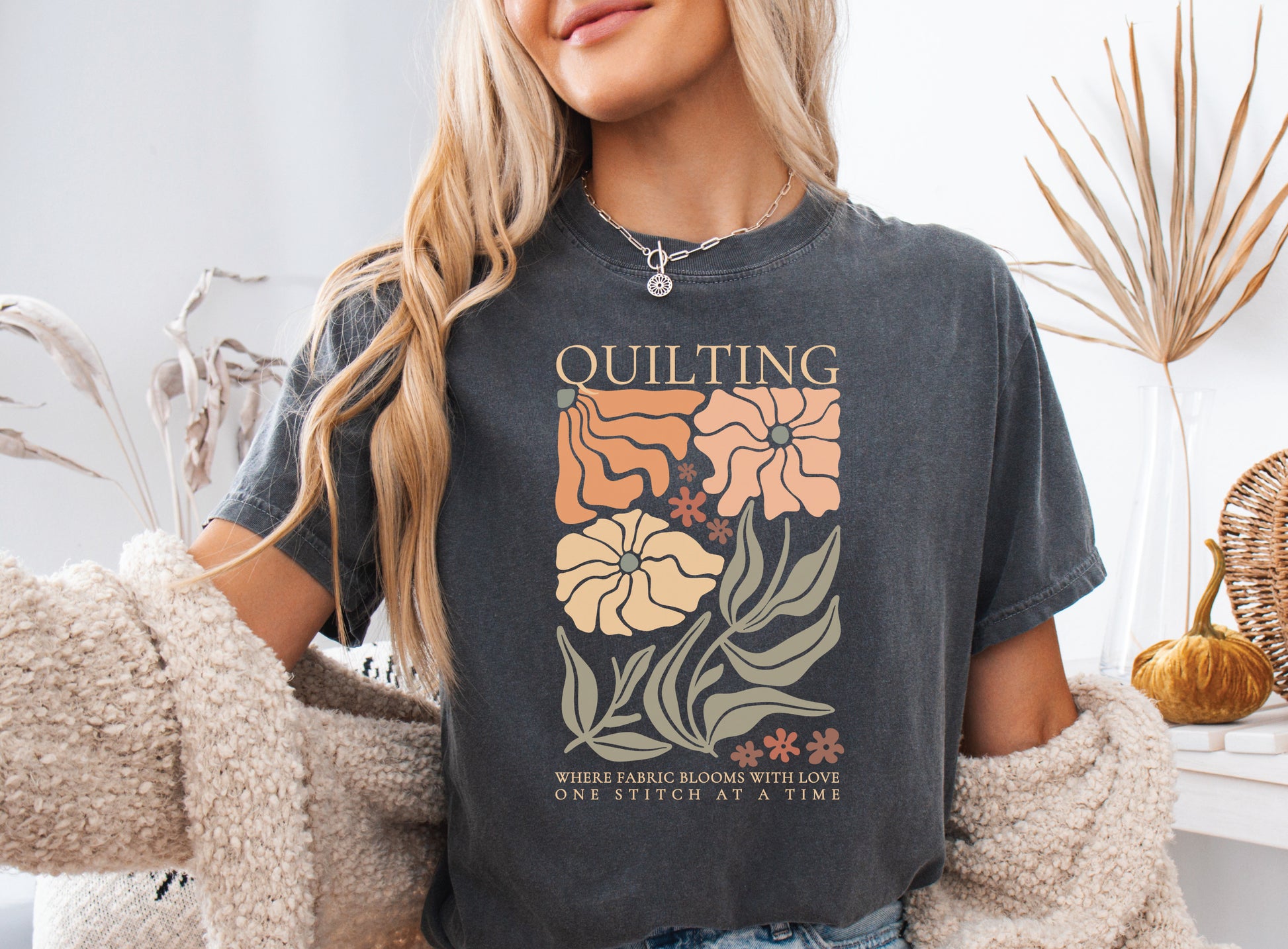 Boho quilting short sleeve t-shirt featuring a floral design and the phrase “Quilting, Where Fabric Blooms With Love, One Stitch at a Time.” 