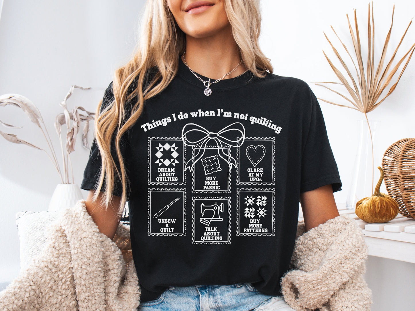 A soft, and cozy t-shirt featuring the phrase “Things I Do When I’m Not Quilting” with stitched-style icons showing humorous quilting activities like buying fabric, dreaming of quilts, and unsewing.