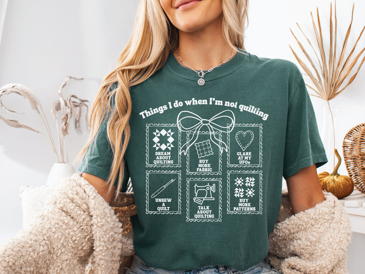 A soft, and cozy t-shirt featuring the phrase “Things I Do When I’m Not Quilting” with stitched-style icons showing humorous quilting activities like buying fabric, dreaming of quilts, and unsewing.
