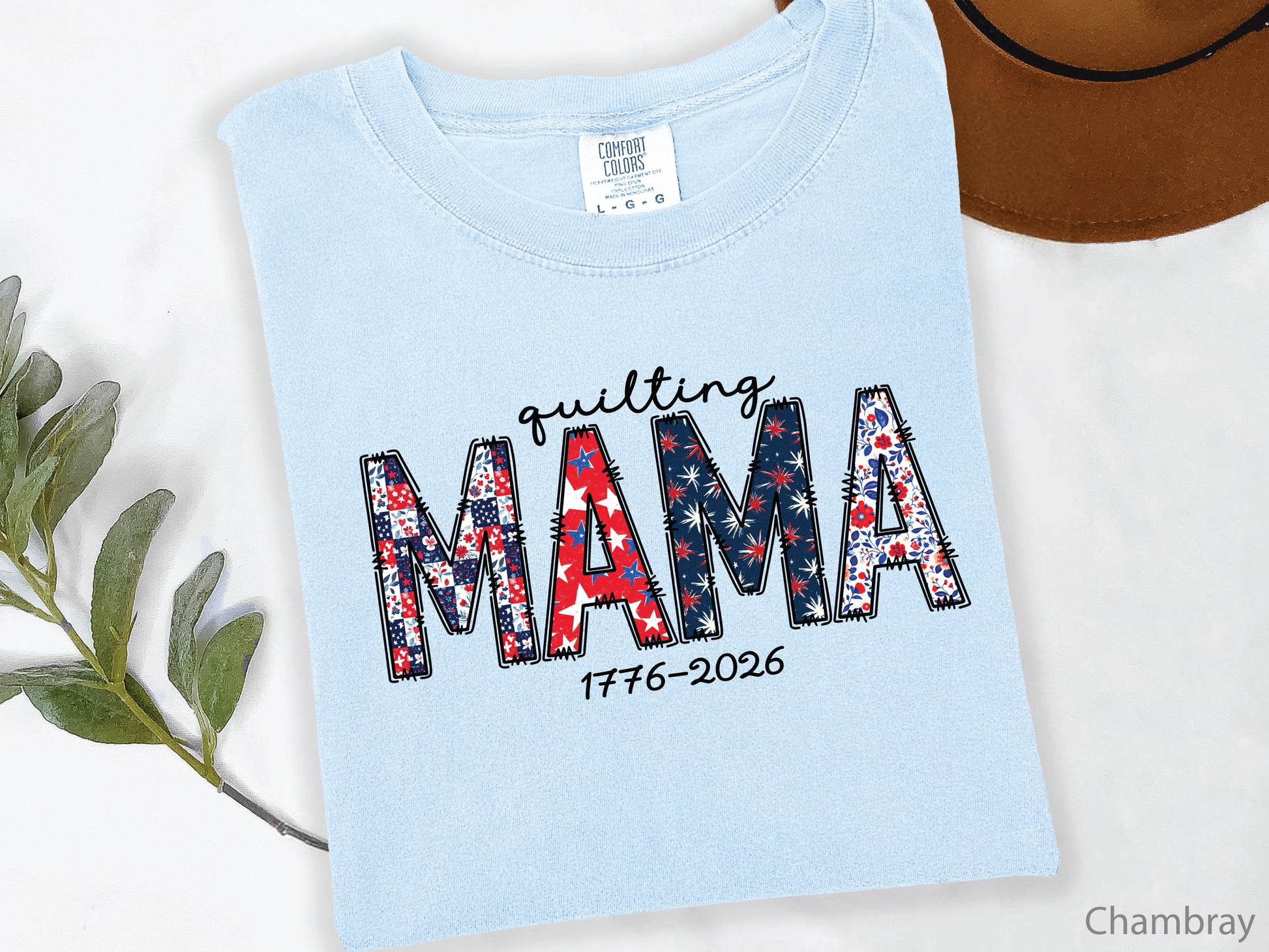 White t-shirt with Quilting Mama design in red, white, and blue patchwork lettering with stitched details, perfect for quilters and Mother’s Day gifts.