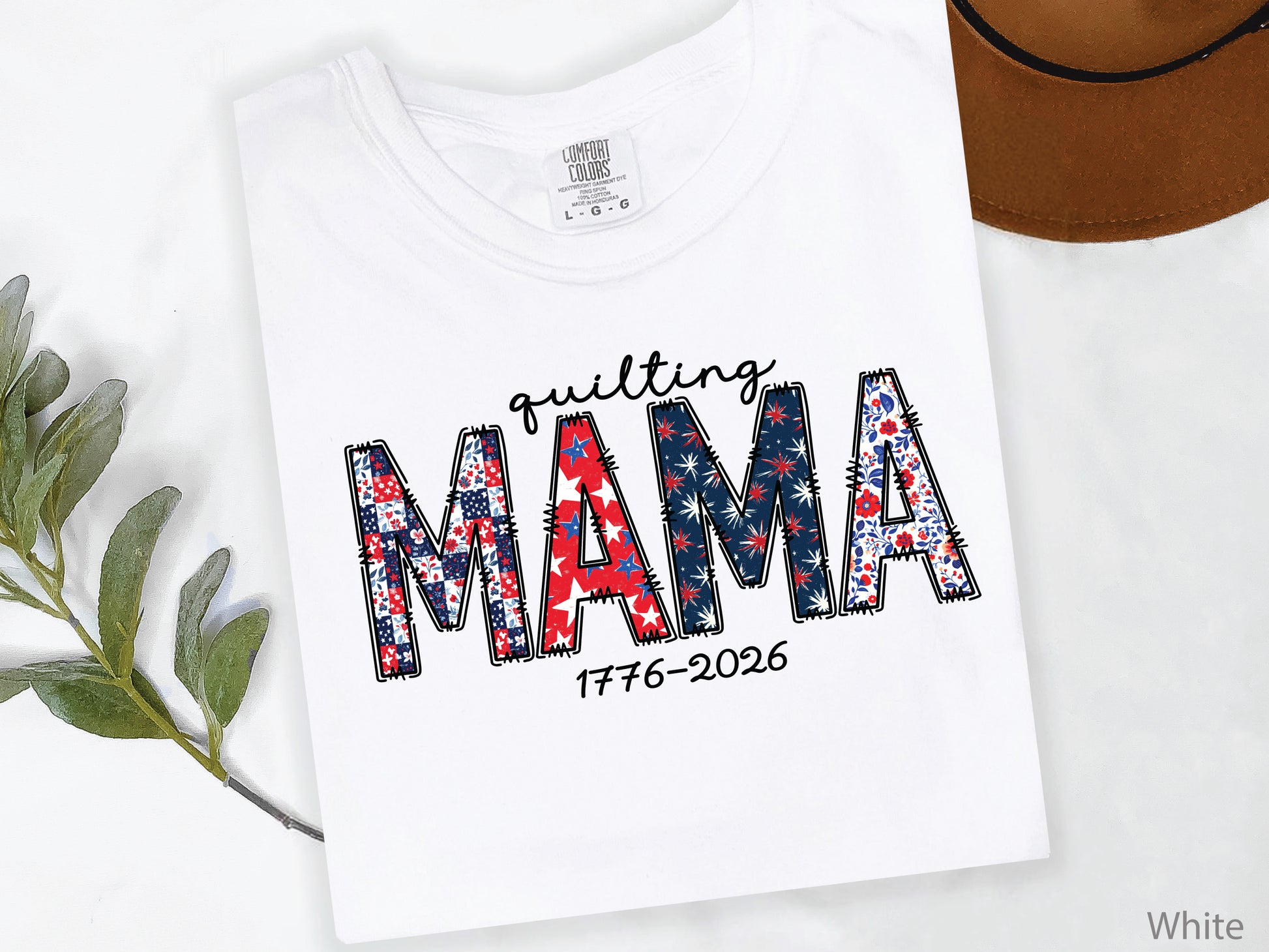 White t-shirt with Quilting Mama design in red, white, and blue patchwork lettering with stitched details, perfect for quilters and Mother’s Day gifts.