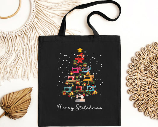 Black canvas tote bag featuring a festive Christmas tree made of sewing machines printed on both sides. A holiday gift for quilters and sewers from Bee Inspired Tees, perfect for quilt retreats, sewing classes, and everyday use.