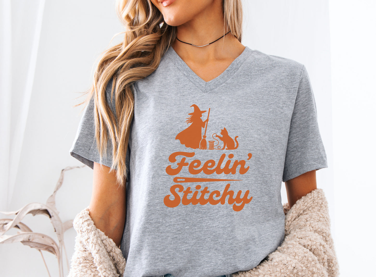 Feelin’ Stitchy Halloween t-shirt featuring a silhouette of a witch with a black cat and spool of thread, designed for sewists, quilters, and stitch witches.