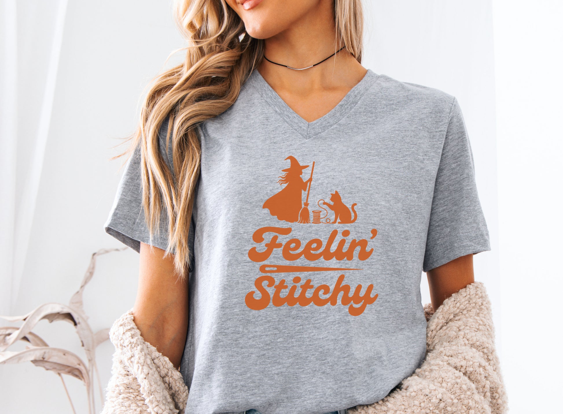 Feelin’ Stitchy Halloween t-shirt featuring a silhouette of a witch with a black cat and spool of thread, designed for sewists, quilters, and stitch witches.