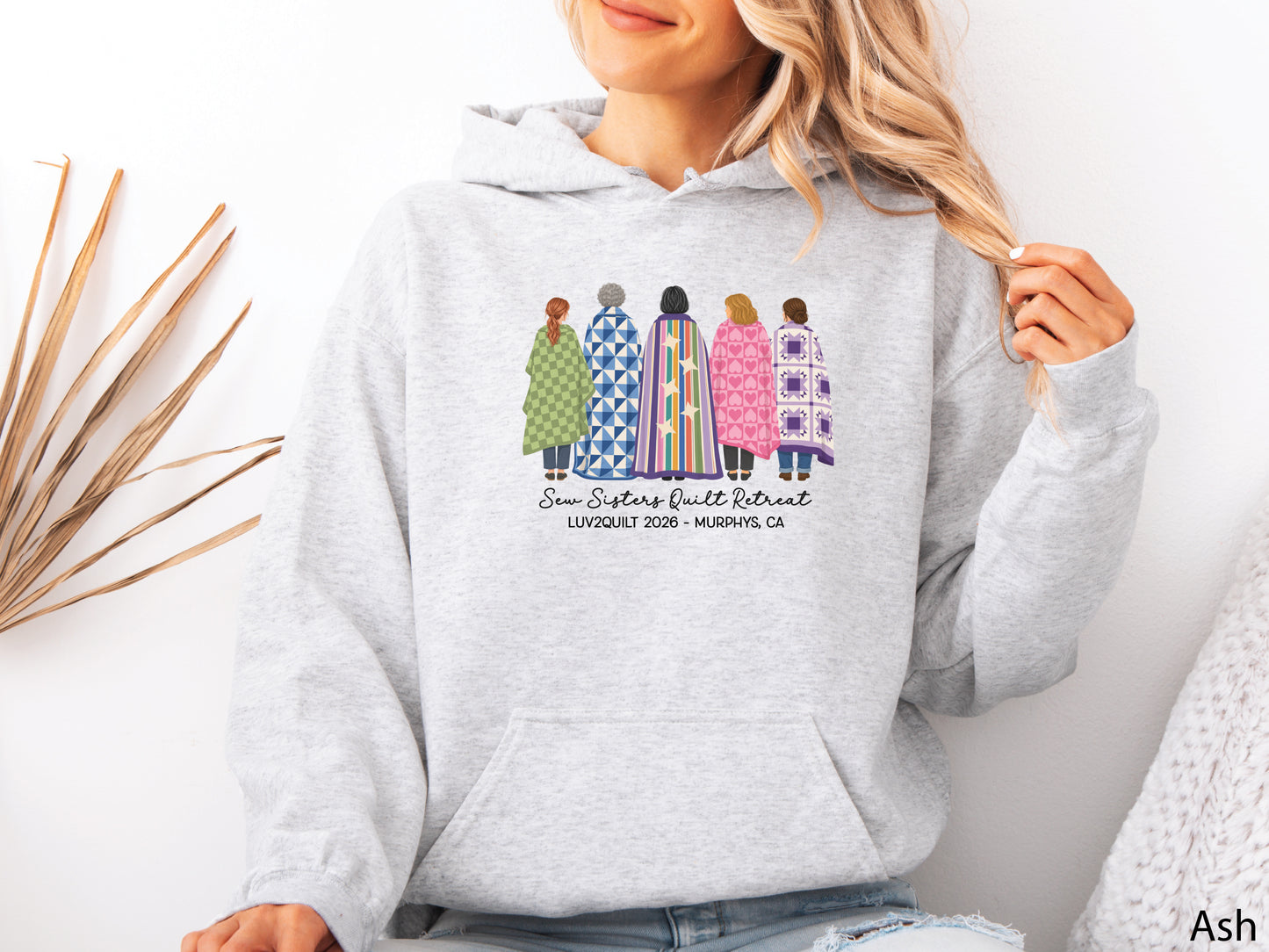 Sew Sisters Quilt Retreat hoodie sweatshirt featuring five quilters wrapped in colorful quilts, personalized for the LUV2QUILT 2026 retreat in Murphys, CA.