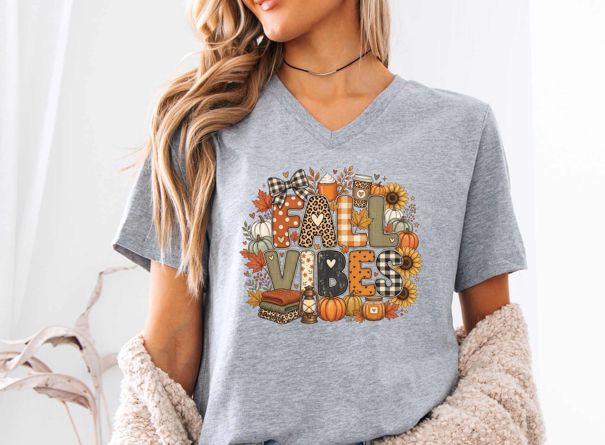 Fall Vibes t-shirt design with patchwork-style lettering, pumpkins, sunflowers, fall leaves, cozy drinks, lantern, candle, and folded blankets.