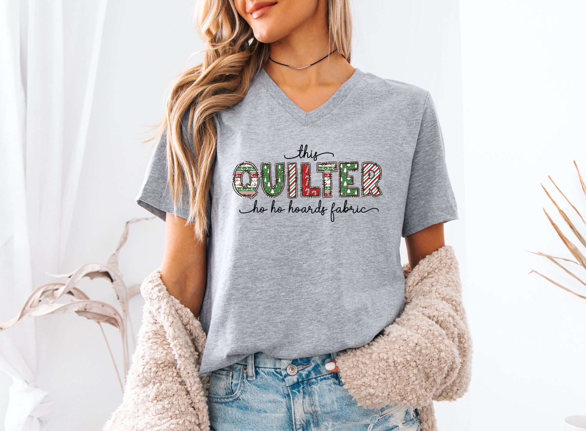 This Quilter Ho Ho Hoards Fabric V-Neck t-shirt with red and green patchwork lettering, a funny Christmas shirt for quilters who love fabric, sewing, and holiday cheer.