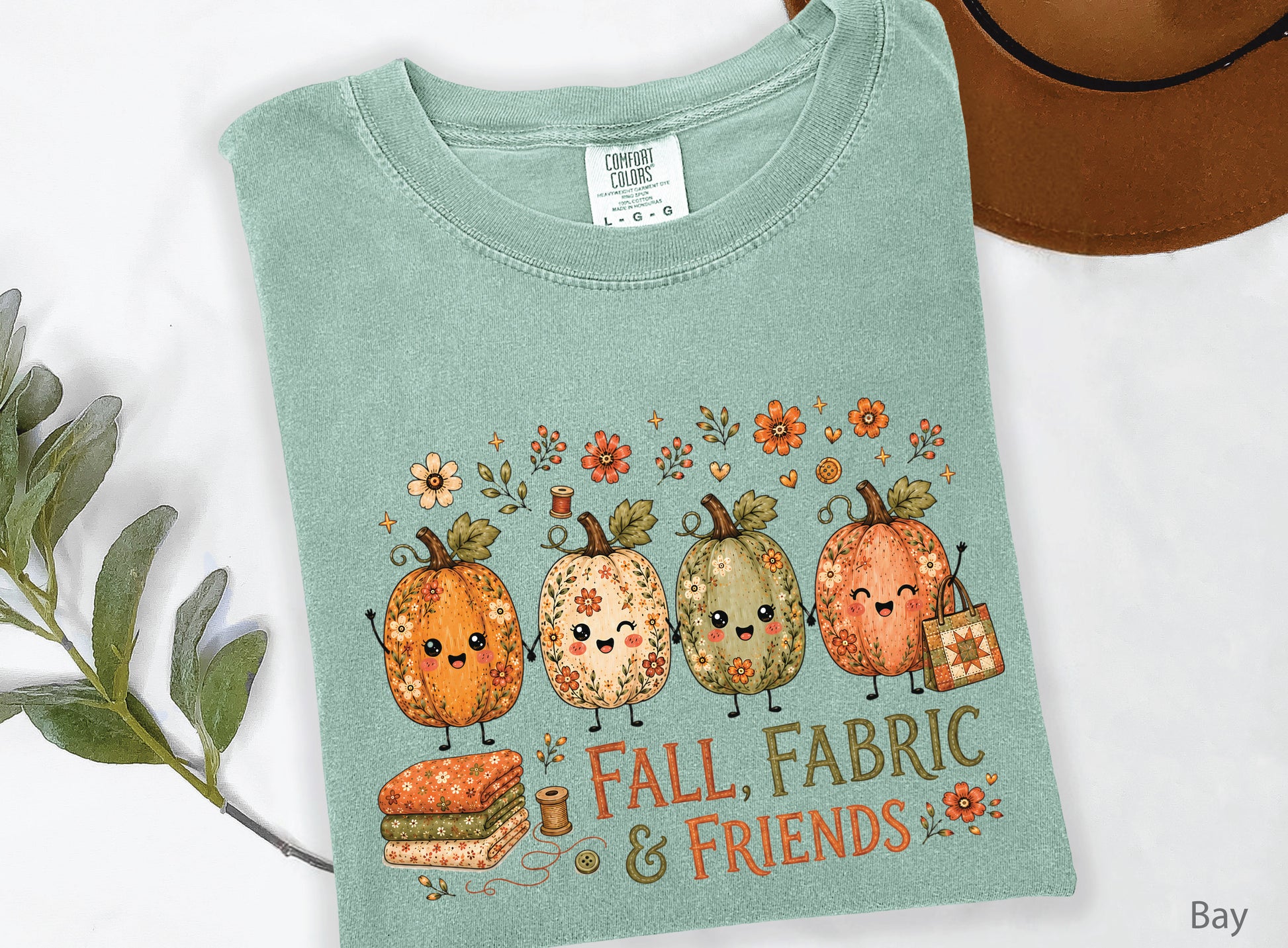 Fall, Fabric & Friends quilting t-shirt featuring four whimsical floral pumpkins, folded fabric, sewing notions, fall flowers, and a patchwork quilt tote.
