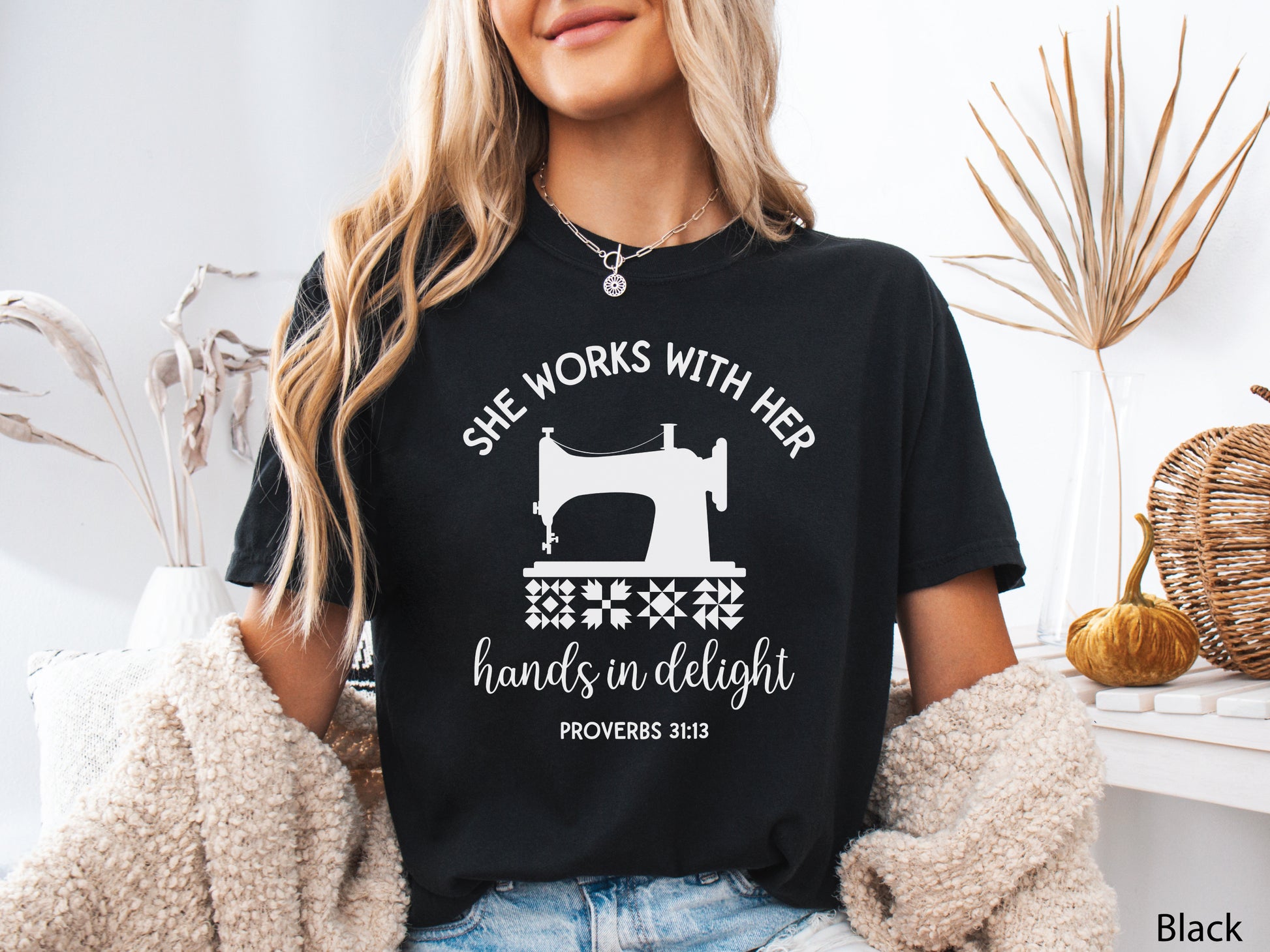 A t-shirt featuring a vintage-style sewing machine, quilt block icons, and the verse “She works with her hands in delight – Proverbs 31:13.”