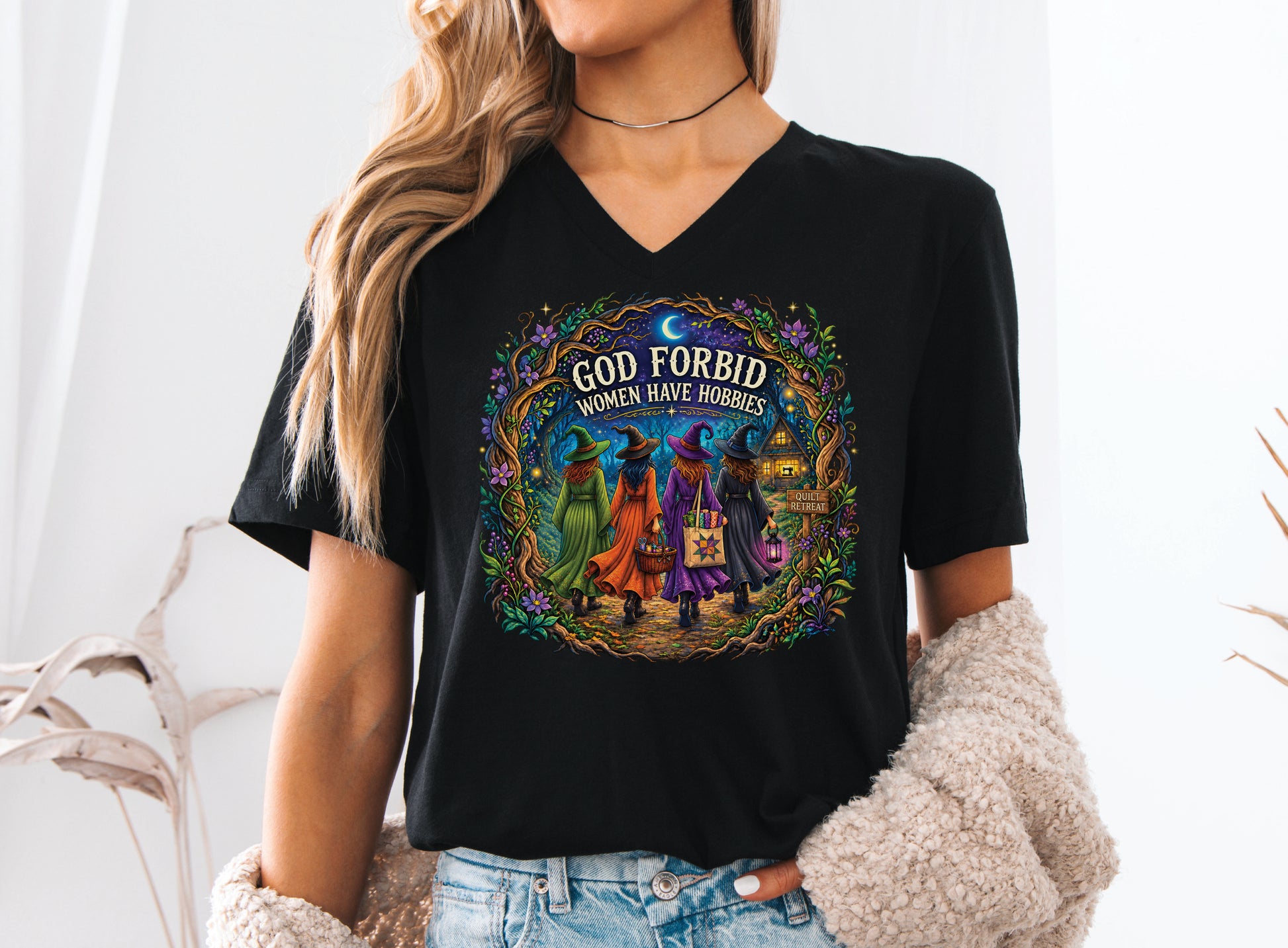 God Forbid Women Have Hobbies Halloween quilting t-shirt featuring four quilty friends dressed as witches walking through an enchanted moonlit forest to a cozy quilt retreat cottage with sewing and quilting details.