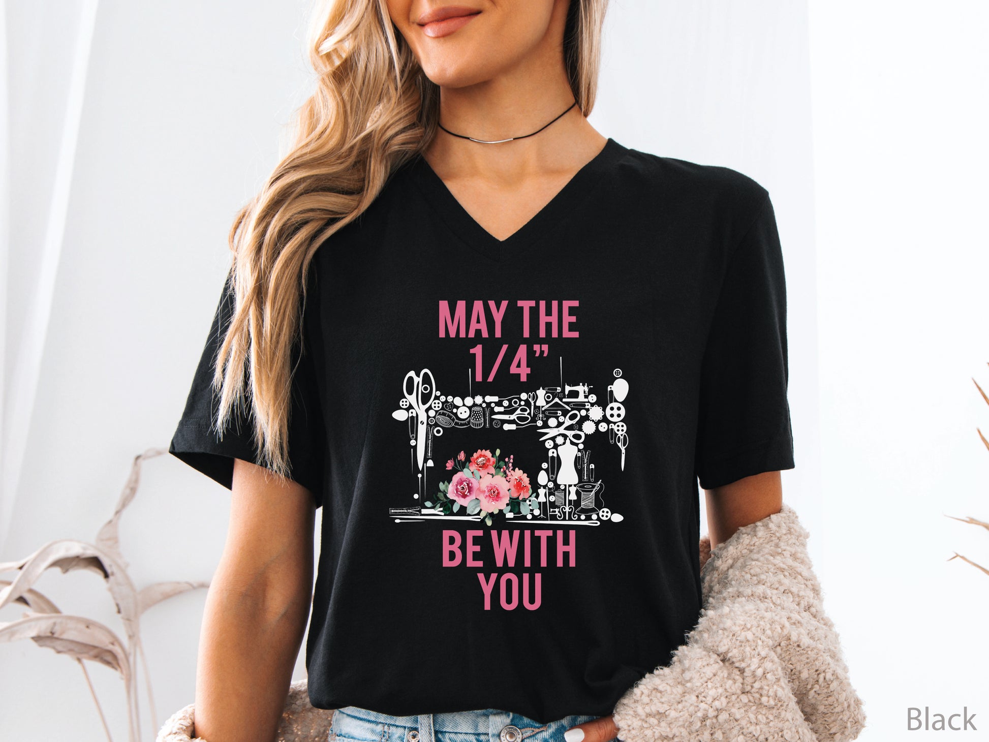 V-neck t-shirt with “May the 1/4” Be With You” quilting design featuring sewing tools arranged in a sewing machine shape with floral accents, ideal for quilters and sewing enthusiasts.