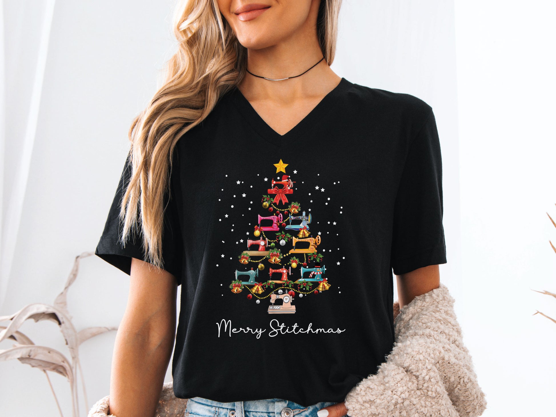 Festive Christmas tree made of colorful sewing machines with the phrase “Merry Stitchmas” on a V-neck t-shirt, a fun holiday gift for quilters and sewing enthusiasts.