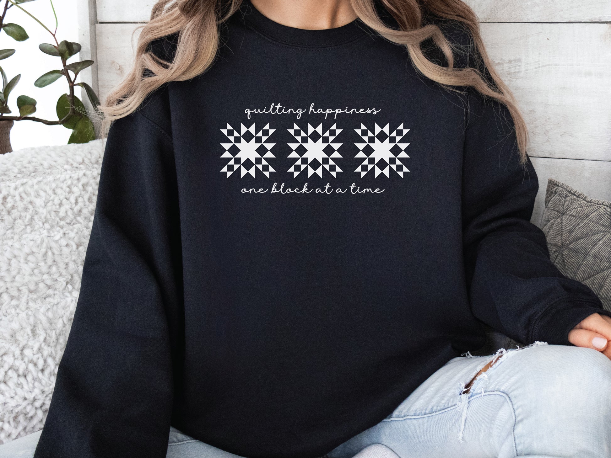 Black unisex sweatshirt with the phrase “Quilting Happiness, One Block at a Time,” designed by Bee Inspired Tees. Cozy fall sweatshirt for quilters, ideal for retreats and gifts for quilting lovers.