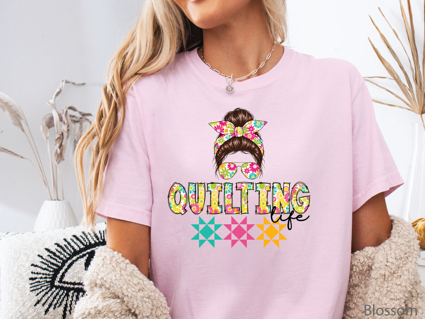 Celebrate your love of quilting with this cheerful Quilting Life t-shirt! Featuring a stylish messy bun, colorful floral headband, coordinating sunglasses, and bright quilt block accents, this fun design is perfect for quilters, fabric lovers, and anyone who feels most at home in their sewing room.