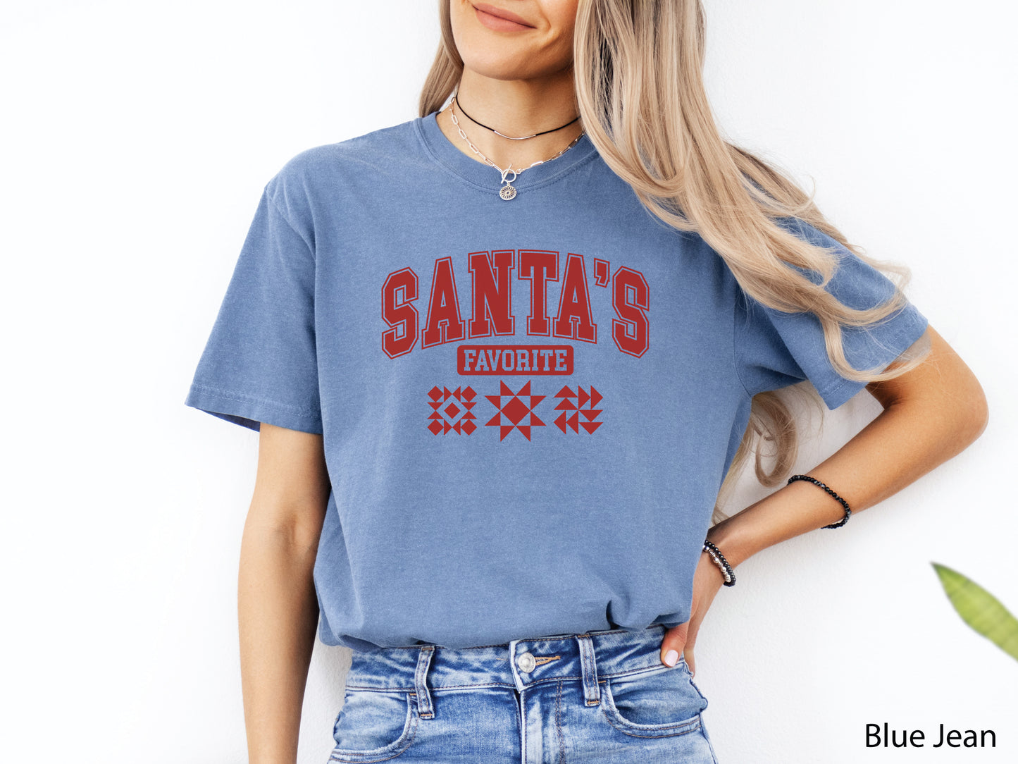 Festive light blue t-shirt with the phrase “Santa’s Favorite” in red varsity letters and three quilt block designs, styled for quilters who love Christmas and handmade gifts.