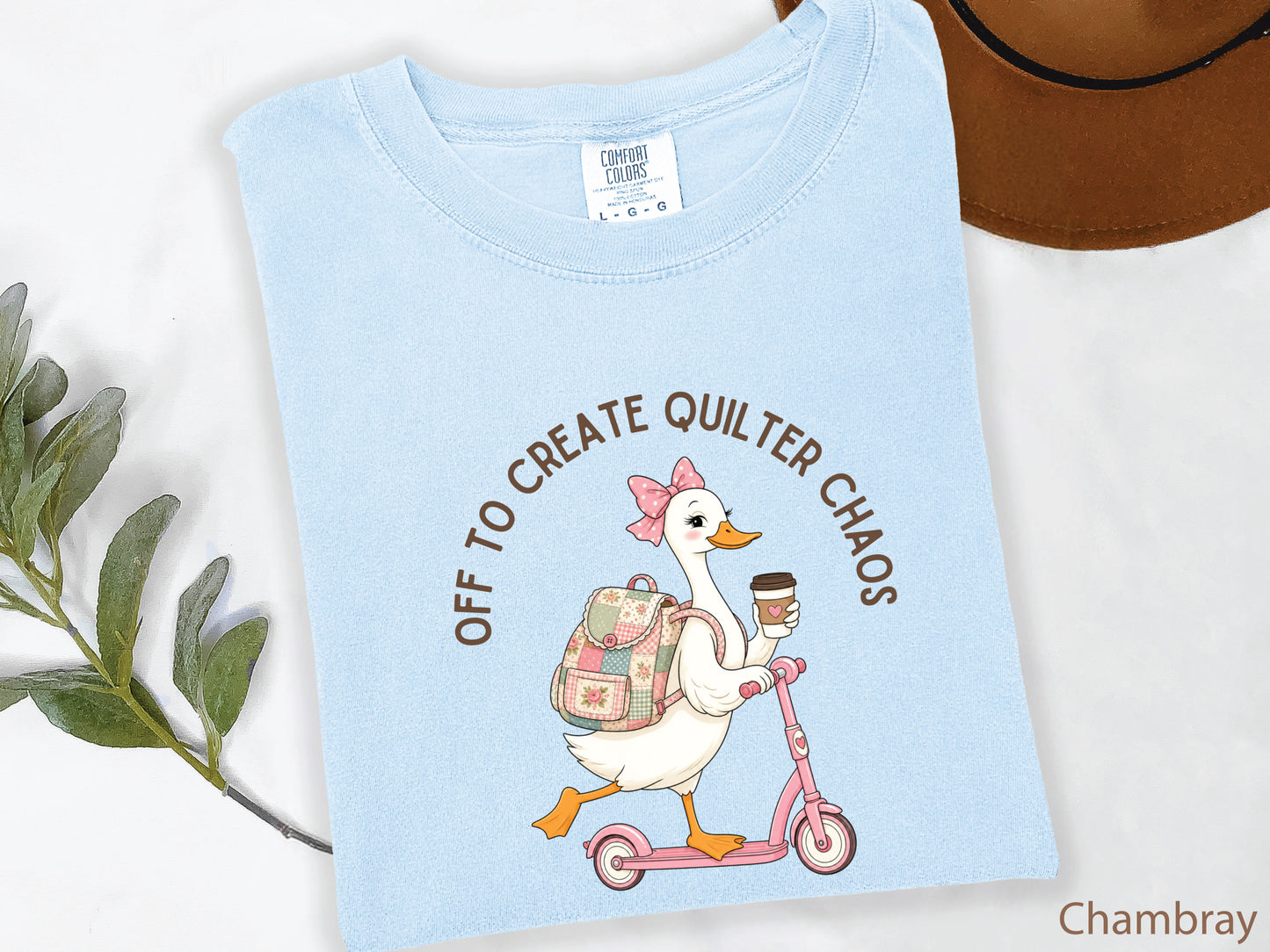 Funny quilting t-shirt featuring a goose riding a pink scooter with coffee and a patchwork backpack, paired with the saying “Off To Create Quilter Chaos.” Perfect for quilters, sewists, quilt retreats, and fabric lovers.