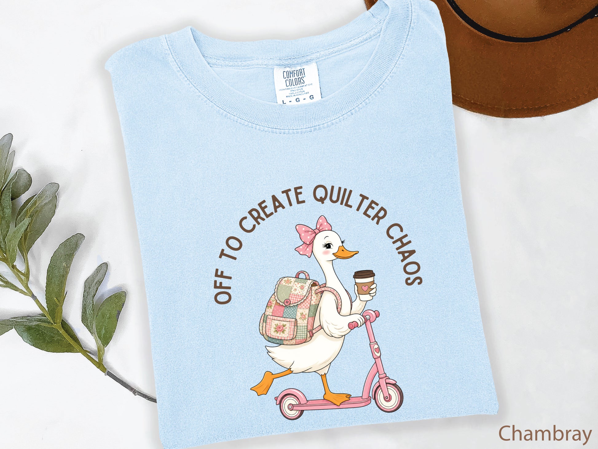 Funny quilting t-shirt featuring a goose riding a pink scooter with coffee and a patchwork backpack, paired with the saying “Off To Create Quilter Chaos.” Perfect for quilters, sewists, quilt retreats, and fabric lovers.