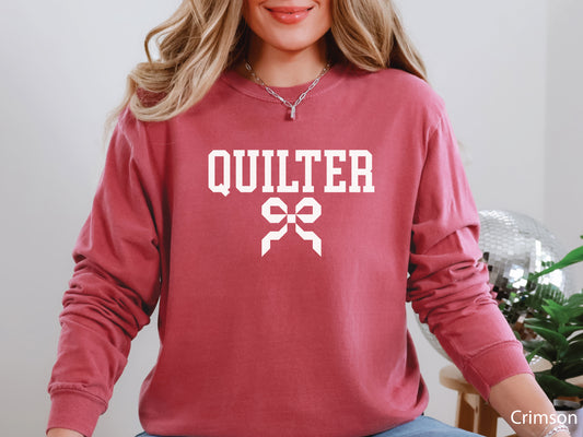 Cozy sweatshirt with bold varsity-style “Quilter” lettering and a coquette bow — perfect for quilt retreats, guild meetings, or as a thoughtful gift for quilters.