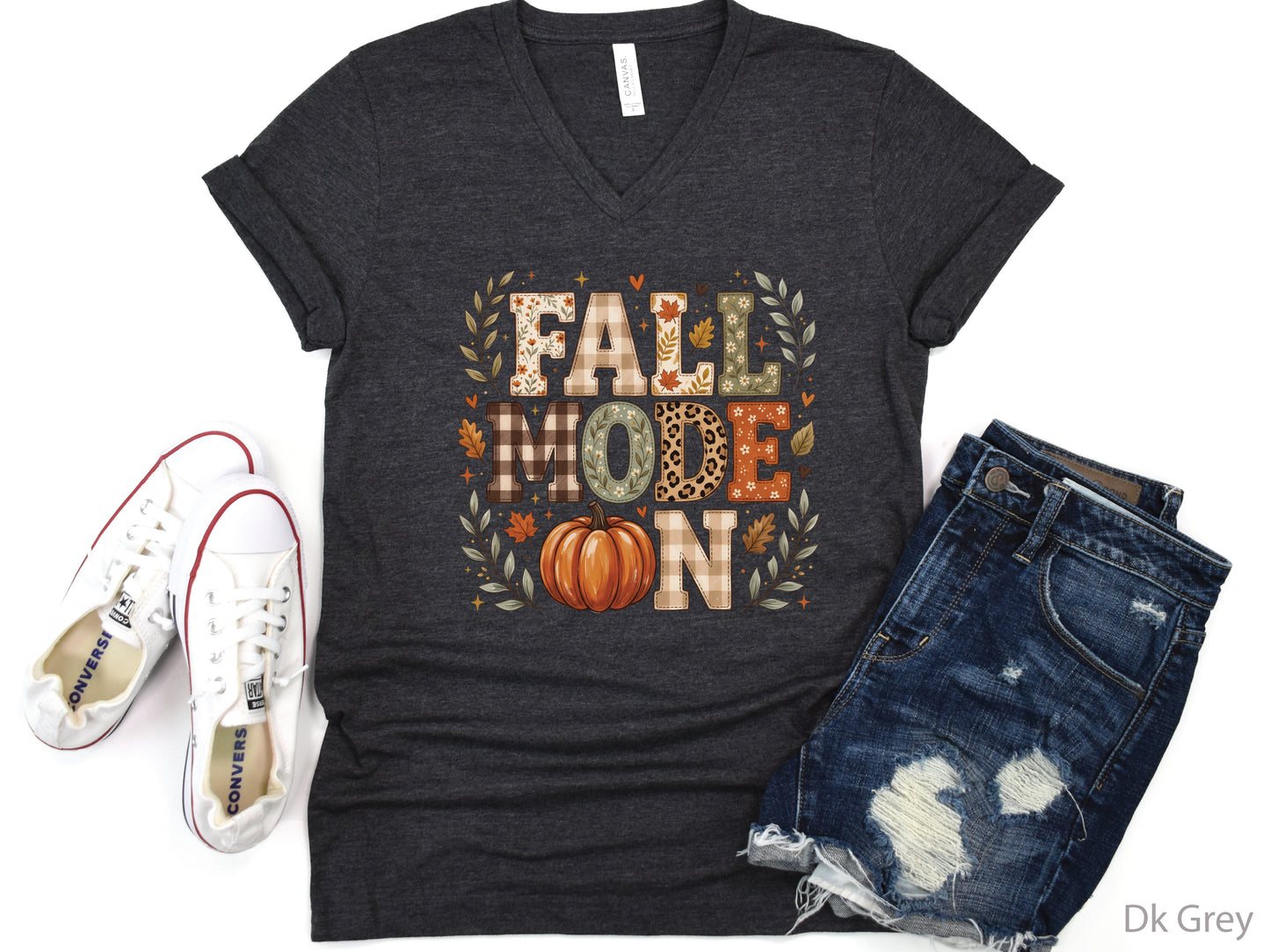 Fall Mode On v-neck t-shirt design featuring patchwork-style lettering with patchwork plaid, floral, leopard print, and fall leaf patterns, plus an orange pumpkin and autumn foliage.
