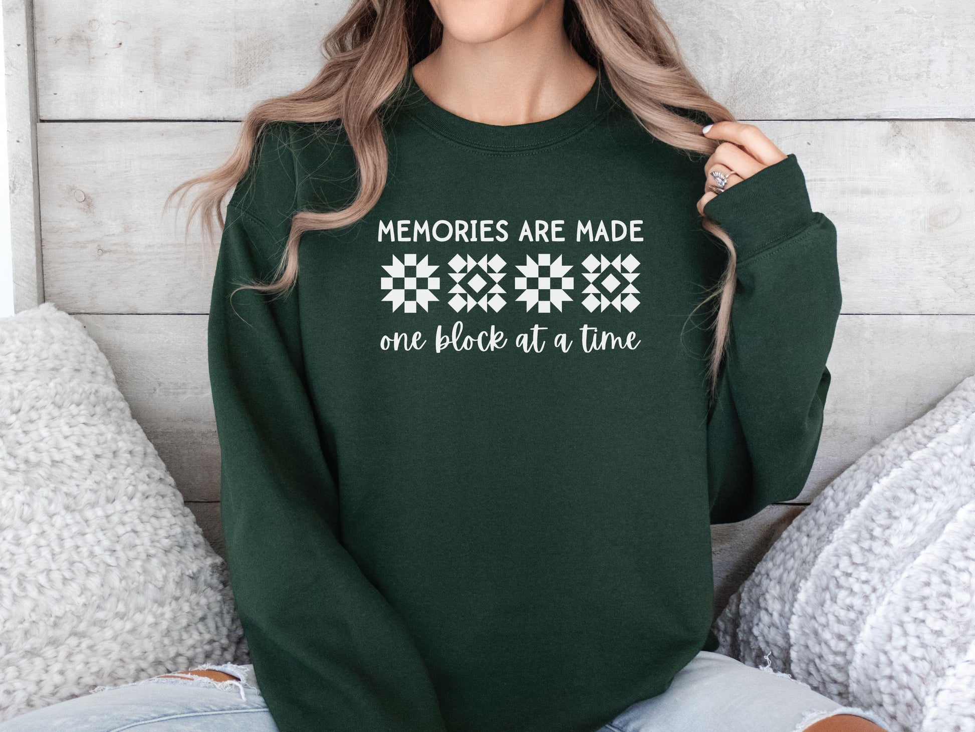 A long-sleeve quilt-themed sweatshirt from Bee Inspired Tees featuring the phrase “Memories Are Made One Block at a Time,” perfect for cozy sewing days, quilt retreats, or gifting to quilters who love celebrating their craft.