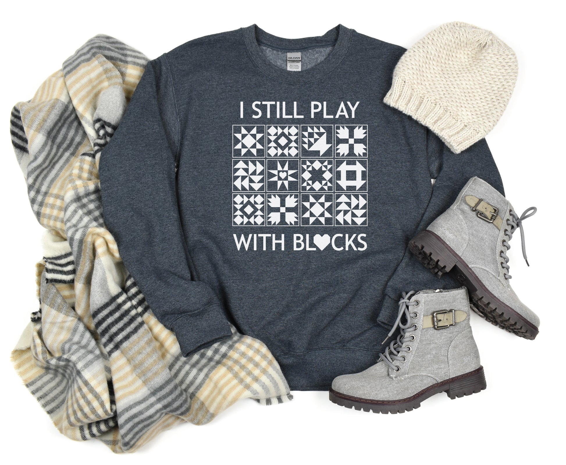 A cozy sweatshirt with quilt block designs with the phrase “I Still Play With Blocks” — ideal for winter sewing sessions.
