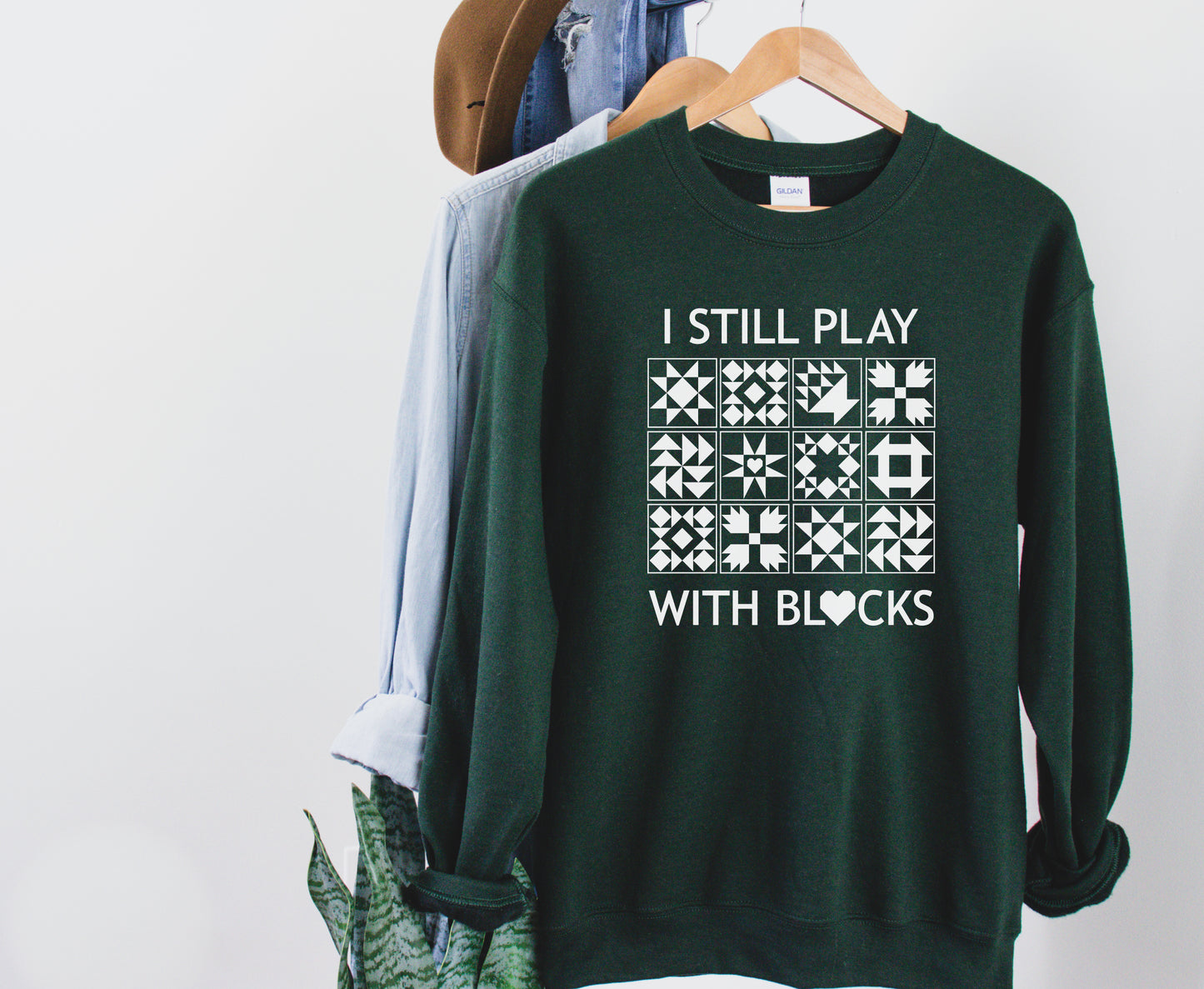 A cozy sweatshirt with quilt block designs with the phrase “I Still Play With Blocks” — ideal for winter sewing sessions.