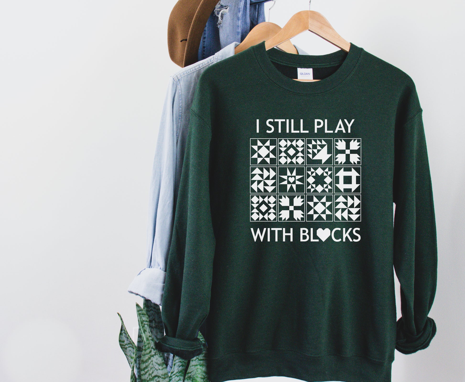 A cozy sweatshirt with quilt block designs with the phrase “I Still Play With Blocks” — ideal for winter sewing sessions.