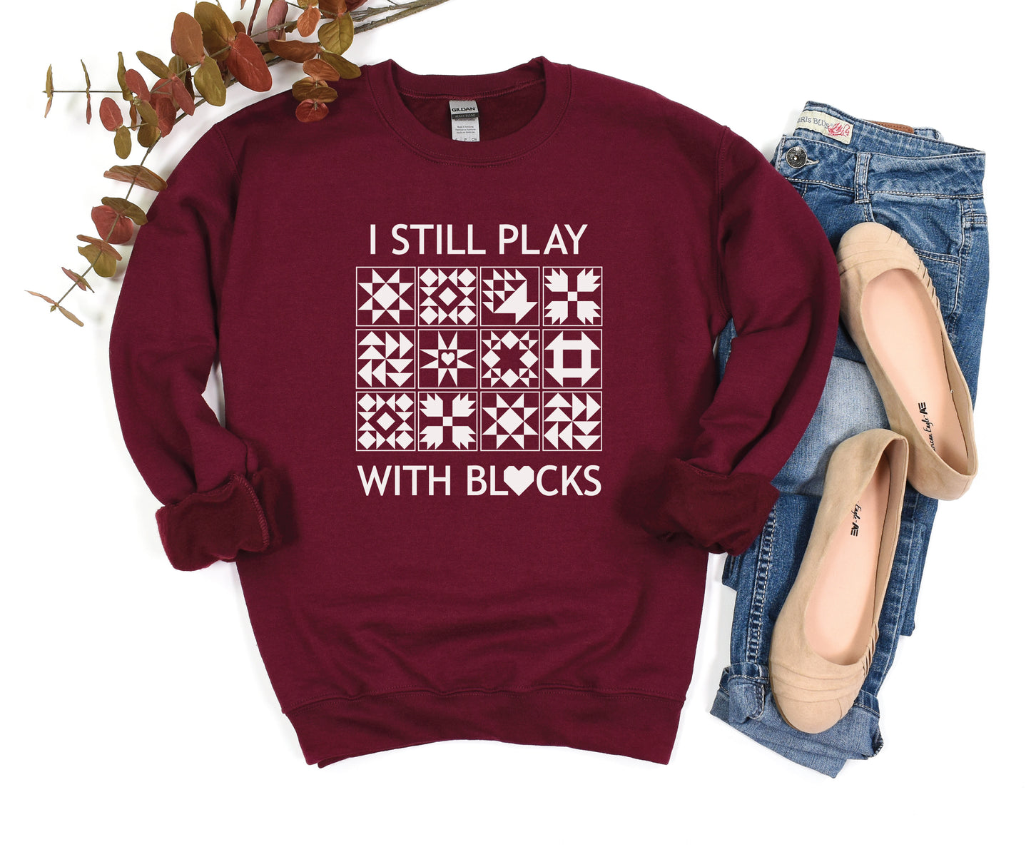 A cozy sweatshirt with quilt block designs with the phrase “I Still Play With Blocks” — ideal for winter sewing sessions.