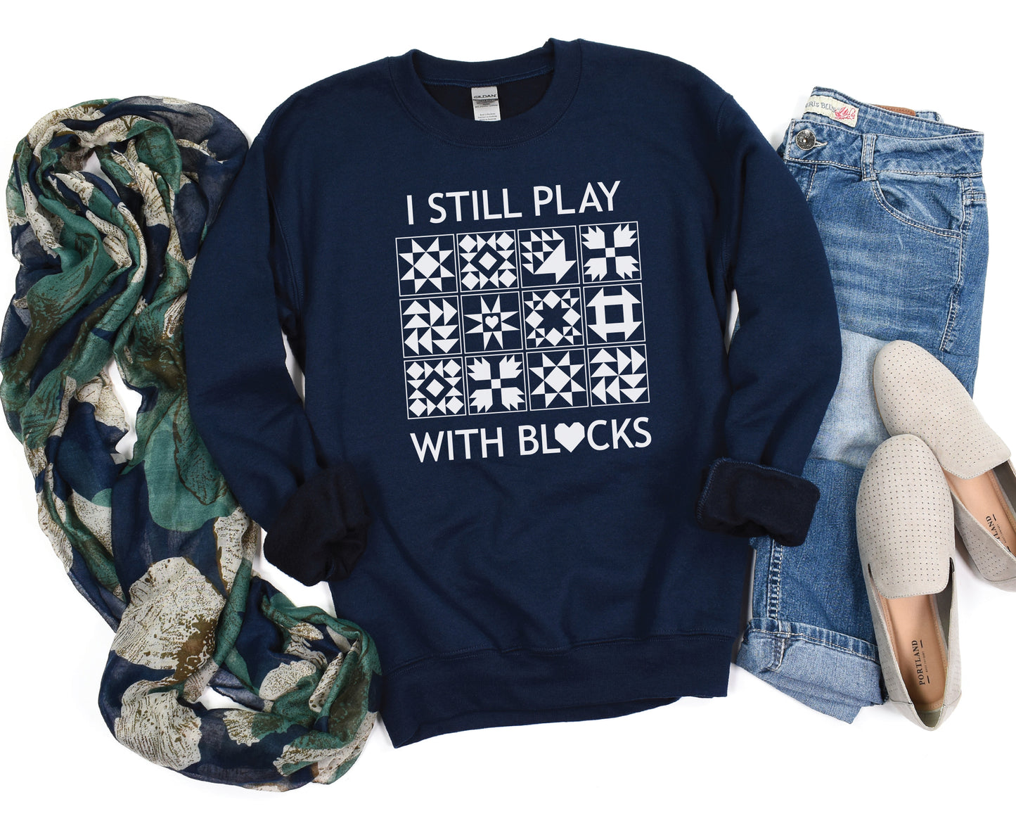 A cozy sweatshirt with quilt block designs with the phrase “I Still Play With Blocks” — ideal for winter sewing sessions.