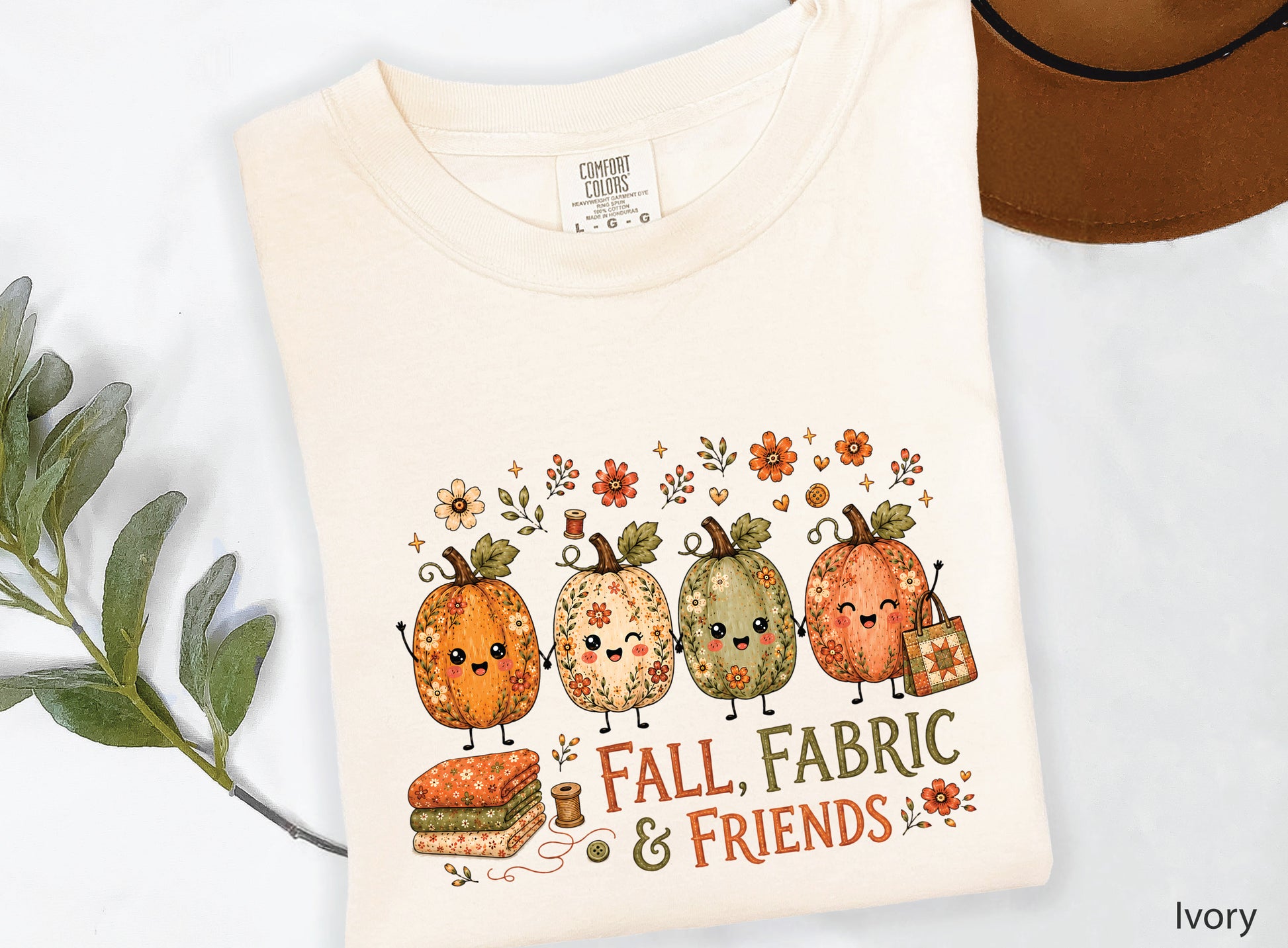 Fall, Fabric & Friends quilting t-shirt featuring four whimsical floral pumpkins, folded fabric, sewing notions, fall flowers, and a patchwork quilt tote.