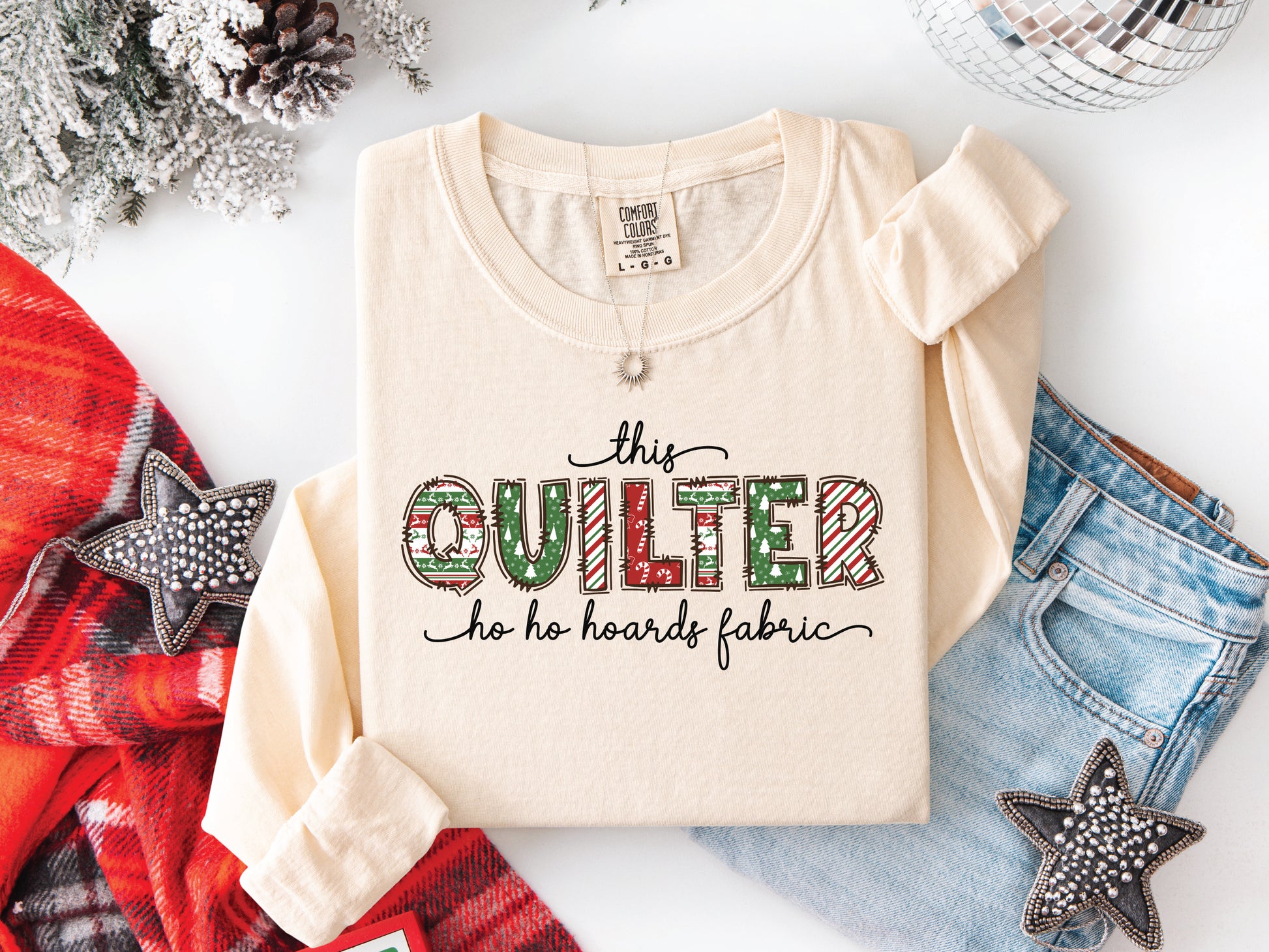 This Quilter Ho Ho Hoards Fabric long sleeve t-shirt with red and green patchwork lettering, a funny Christmas shirt for quilters who love fabric, sewing, and holiday cheer.