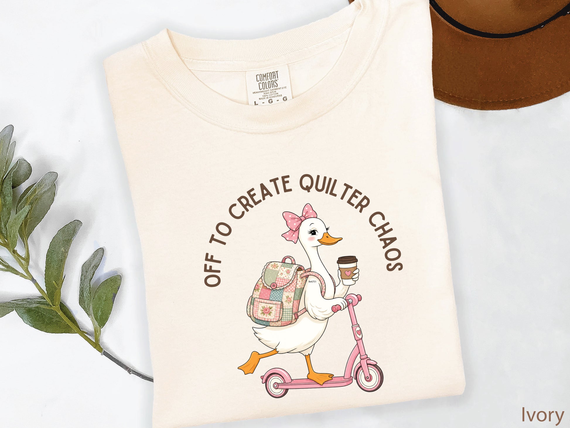 Funny quilting t-shirt featuring a goose riding a pink scooter with coffee and a patchwork backpack, paired with the saying “Off To Create Quilter Chaos.” Perfect for quilters, sewists, quilt retreats, and fabric lovers.