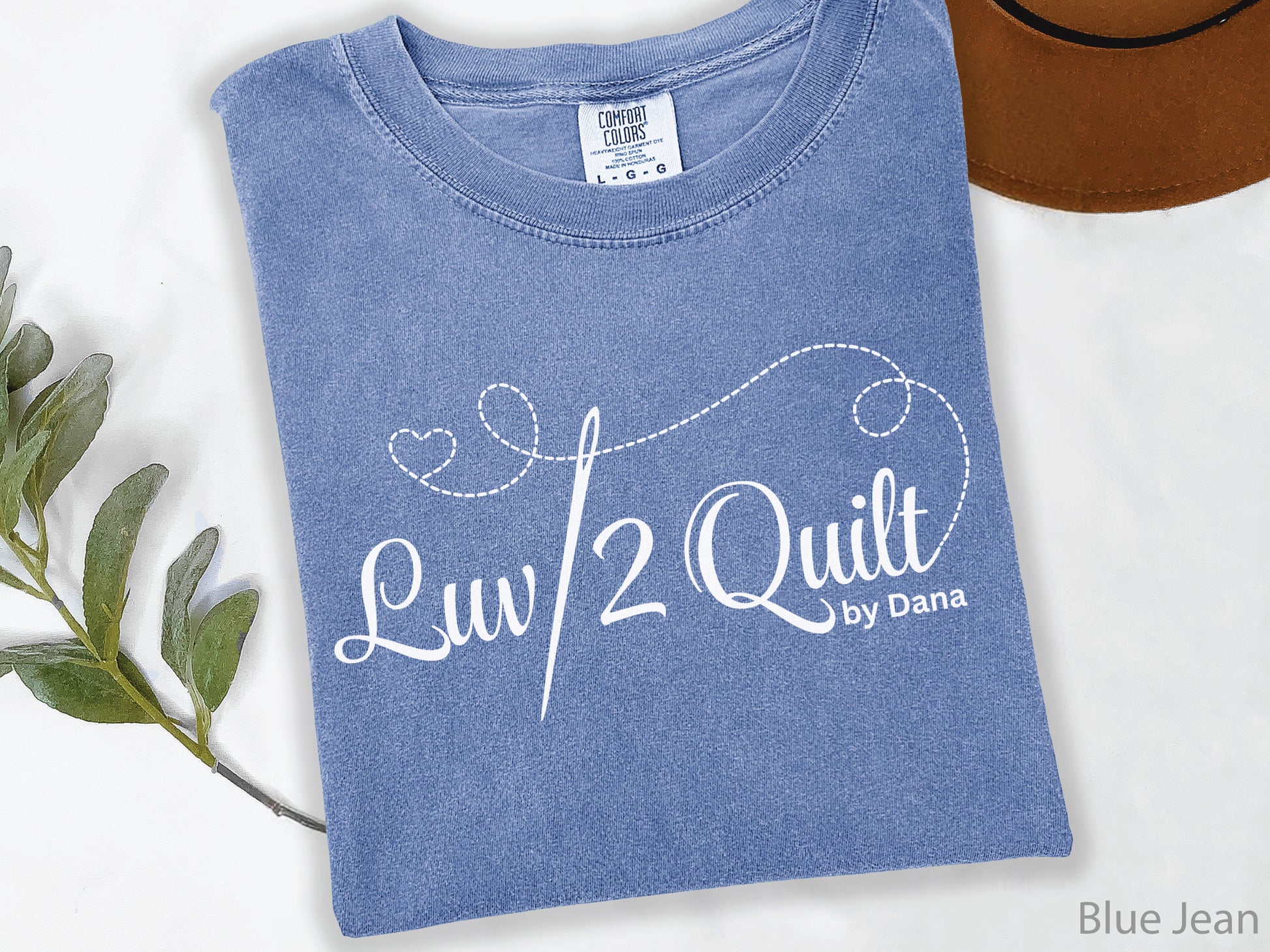 Official Luv2Quilt by Dana quilting-themed t-shirt featuring the Luv2Quilt logo with a sewing needle and stitched heart design, perfect for quilt classes, retreats, and everyday wear.