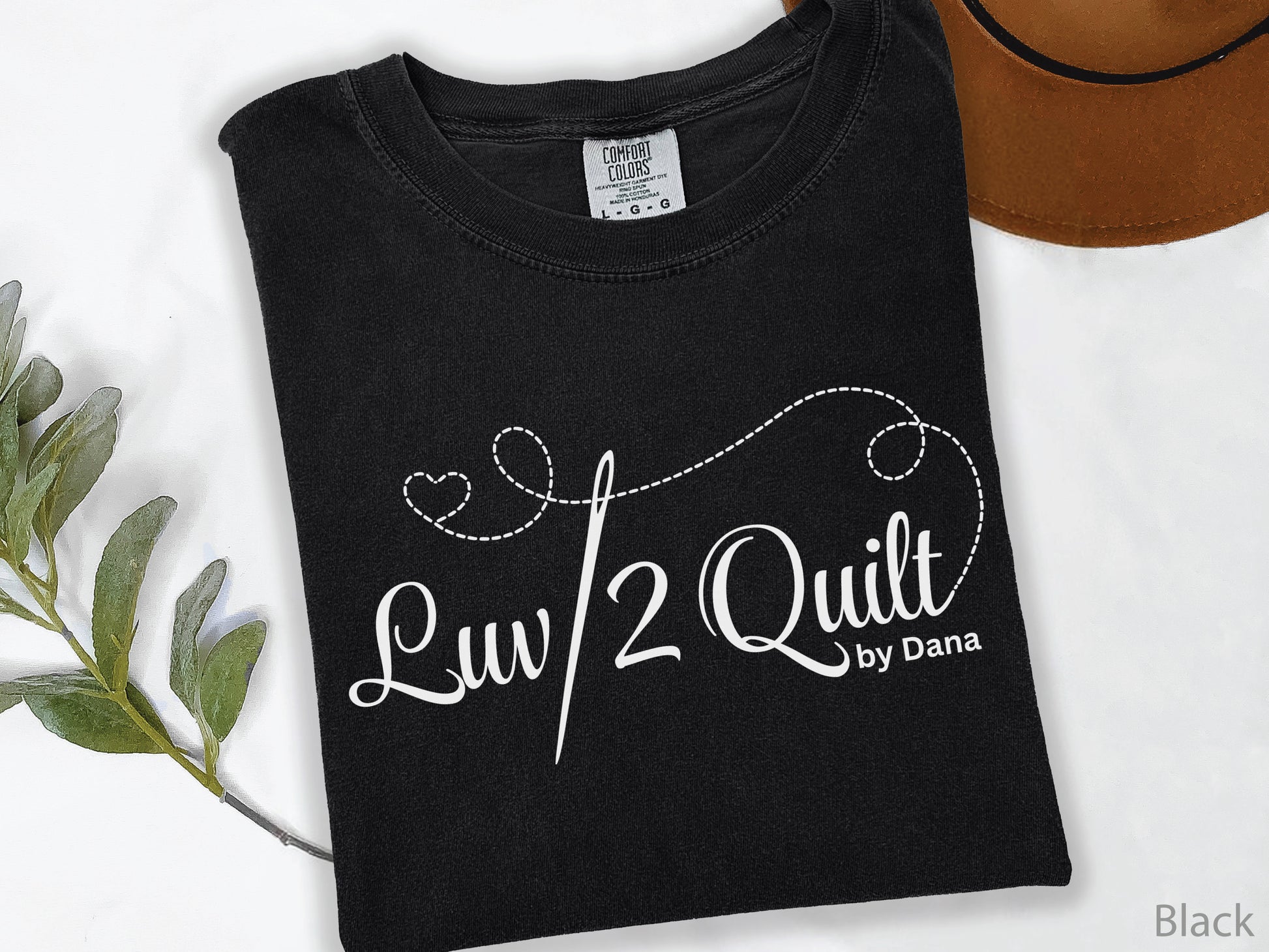 Official Luv2Quilt by Dana quilting-themed t-shirt featuring the Luv2Quilt logo with a sewing needle and stitched heart design, perfect for quilt classes, retreats, and everyday wear.